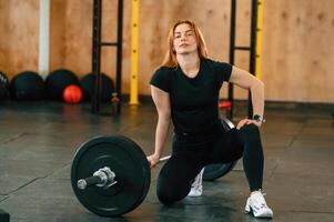 Sitting with barbell on the floor. Beautiful strong ,woman is in the gym photo