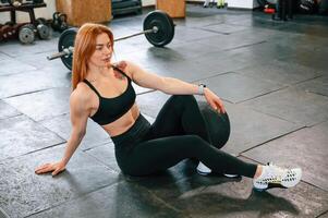 Sitting on ,the floor. Beautiful strong woman is in the gym photo