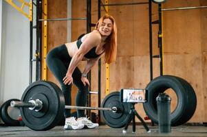 With ,barbell. Shooting by smartphone. Beautiful strong woman is in the gym photo