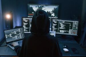 Young, professional, female hacker is indoors by computer with lot of information on displays photo