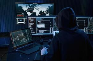 Dark room. Young, professional female hacker is indoors by computer with lot of information on displays photo