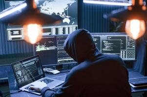 Rear view. .Male professional hacker is sitting by computer, conception of virus photo