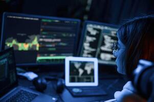 Phishing, attack.. Young professional female hacker is indoors by computer with lot of information on displays photo