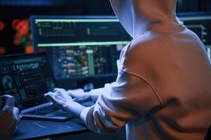 Phishing, attack. Young professional female, hacker is indoors by computer with lot of information on displays photo