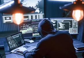 Rear, view. Male professional hacker is sitting by computer, conception of virus photo
