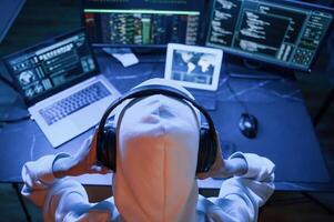 Blue neon light.. Young professional female hacker is indoors by computer with lot of information on displays photo