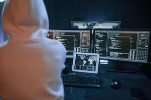 Young professional ,female hacker is indoors by computer with lot of information on displays photo