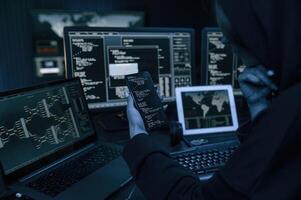 Holding, smartphone with code. Young professional female hacker is indoors by computer with lot of information on displays photo