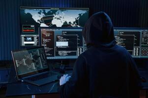 Dark, room. Young professional female hacker is indoors by computer with lot of information on displays photo