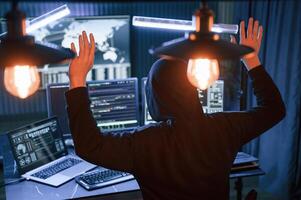Got, caught.. With hands up. Male professional hacker is sitting by computer, conception of virus photo
