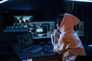Dark, room.. Young professional female hacker is indoors by computer with lot of information on displays photo