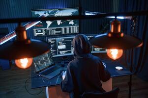 Light bulbs. Young professional, female, hacker is indoors by computer with lot of information on displays photo
