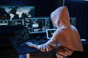 View, from behind. Young ,professional female hacker is indoors by computer with lot of information on displays photo