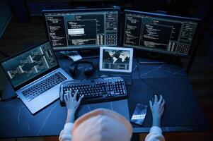 Phishing attack. Young professional ,female ,hacker is indoors by computer with lot of information on displays photo