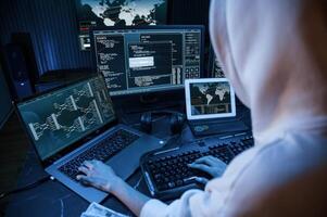 Phishing attack. Young professiona,l female ,hacker is indoors by computer with lot of information on displays photo