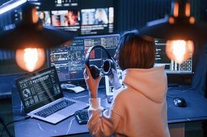 Artificial l,ighting. .Young professional female hacker is indoors by computer with lot of information on displays photo