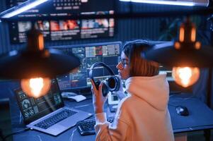 Artificial lighting. Young ,professional ,female hacker is indoors by computer with lot of information on displays photo