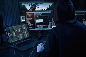 Dark room. Young professional female hacker is indoors by computer with lot of information on displays photo