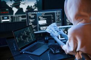 View, from ,behind.. Young professional female hacker is indoors by computer with lot of information on displays photo