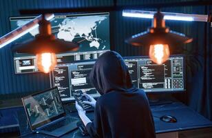 Modern technology. .Young professional female hacker is indoors by computer with lot of information on displays photo