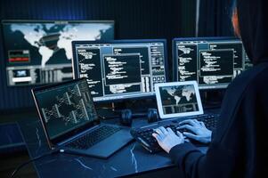 Information on screens. Young professional female hacker is indoors by computer with lot of information on displays,, photo