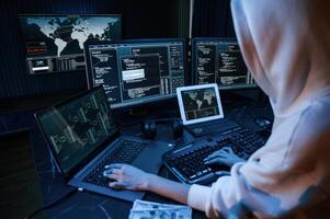 Phishing attack. Young professional female hacker is indoors by computer with lot of information on displays photo