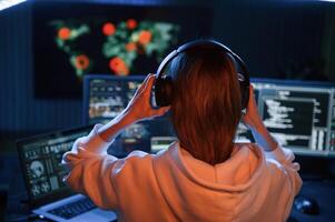 A lot, of ,information on displays. Young professional female hacker is indoors by computer photo