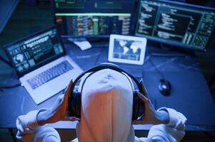 Blue, neon, light. Young professional female hacker is indoors by computer with lot of information on displays photo