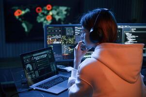 A lot, of information on displays. Young professional female hacker is indoors by computer photo