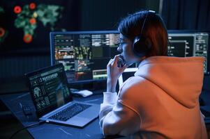 A lot of information on displays. Young, professional, female hacker is indoors by computer photo