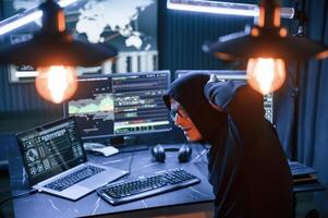 Got caught. With hands up. Male professional hacker is sitting by computer, conception of virus photo