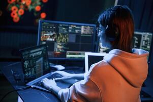 A lot of information ,on, displays. Young professional female hacker is indoors by computer photo