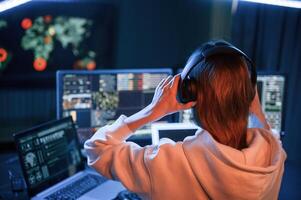 A lot of information on displays. Young professional female hacker is indoors by computer. photo
