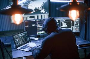 Rear view. Male professional hacker is sitting by computer, conception of virus photo