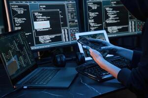 Modern technology. Young professional female hacker is indoors by computer with lot of information on displays photo