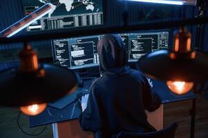 Light bulbs. Young professional, female ,hacker ,is indoors by computer with lot of information on displays photo