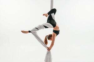 Hanging ,upside, down. Young beautiful woman, doing fly yoga against white background photo