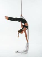 Stretching exercises. Young beautiful woman, doing fly yoga against white background photo