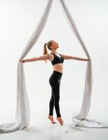 Standing, and, posing. Young beautiful woman doing fly yoga against white background photo