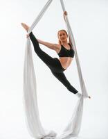 Conception, of flexibility. Young beautiful woman doing fly yoga against white background photo
