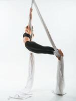 Strong arms ,and legs. In the midair. Young beautiful woman doing fly yoga against white background photo