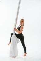 Front view, standing and posing.. Young beautiful, woman doing fly yoga against white background photo