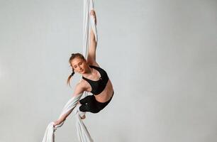 Professional, occupation. Young beautiful woman doing fly yoga against white background photo