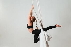 In the, midair. Young beautiful woman doing fly yoga against white background photo