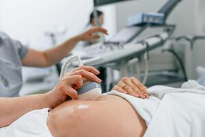 Focused close up view. Pregnant ,woman i,s lying down in the hospital, doctor does ultrasound photo