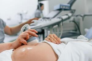 Focused close ,up ,view. Pregnant woman is lying down in the hospital, doctor does ultrasound photo