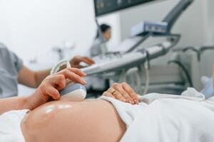 Focused close up, view. Pregnant woman is lying down in the hospital, doctor does ultrasound photo