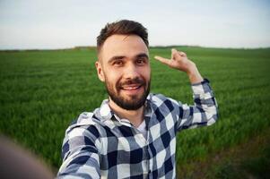 Making ,selfie. Handsome young man, is, on agricultural field photo