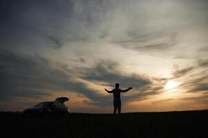 Silhouette of a man that is in ,the, field, at sunset time. Dramatic sky photo