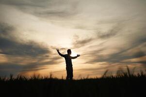 Silhouette of, a man, that is in the field at sunset time. Dramatic sky photo
